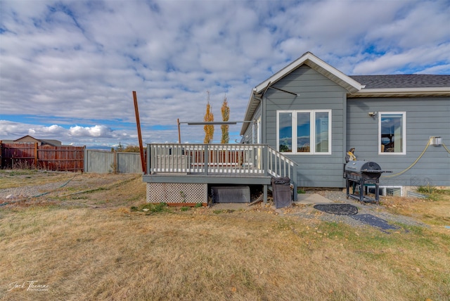 back of property featuring a wooden deck and a yard