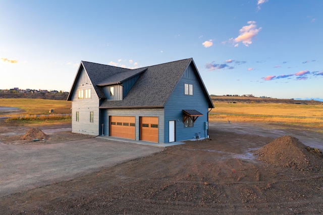 property exterior at dusk featuring a rural view and a garage