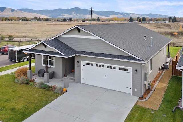 ranch-style house with a garage, a front lawn, cooling unit, a mountain view, and a rural view