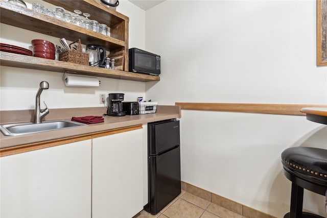 bar featuring white cabinetry, light tile patterned floors, black appliances, and sink