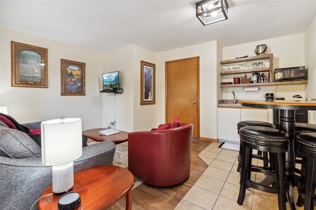 living room with indoor wet bar, a textured ceiling, and light wood-type flooring