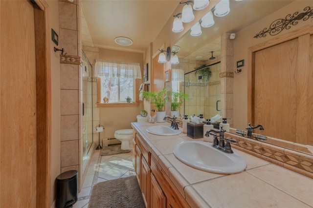 bathroom featuring a baseboard heating unit, toilet, a shower with shower door, vanity, and tile patterned floors