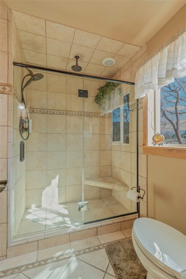 bathroom featuring toilet, tile patterned floors, and a shower with shower door