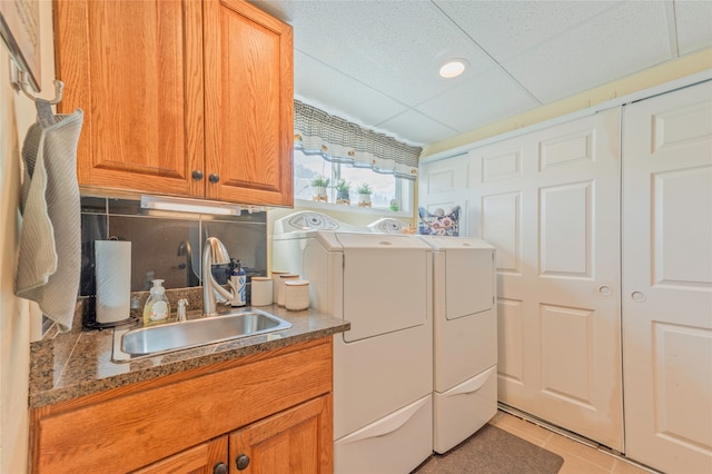 laundry area with sink, washing machine and dryer, cabinets, and light tile patterned floors