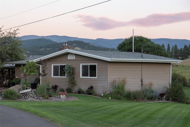 property exterior at dusk featuring a mountain view and a lawn