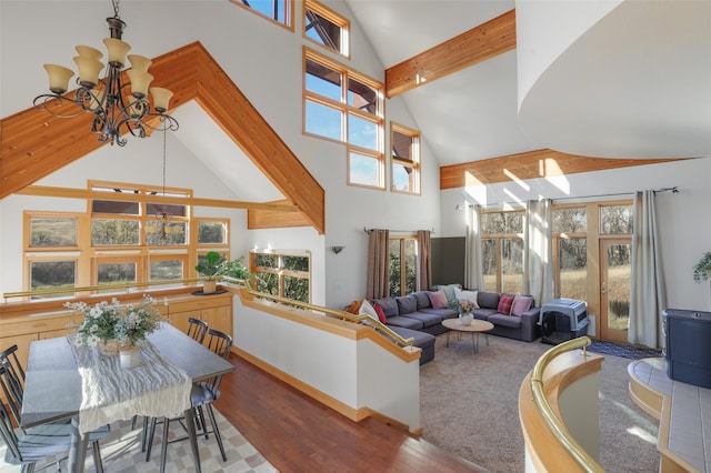 living room with beam ceiling, hardwood / wood-style flooring, plenty of natural light, and an inviting chandelier