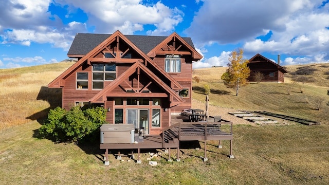 rear view of house with a yard, a hot tub, and a deck