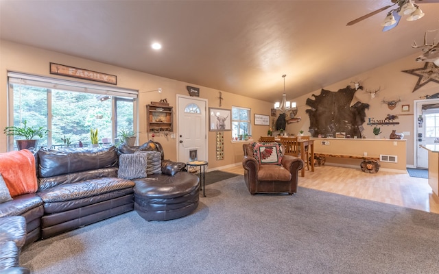 carpeted living room with vaulted ceiling and ceiling fan with notable chandelier