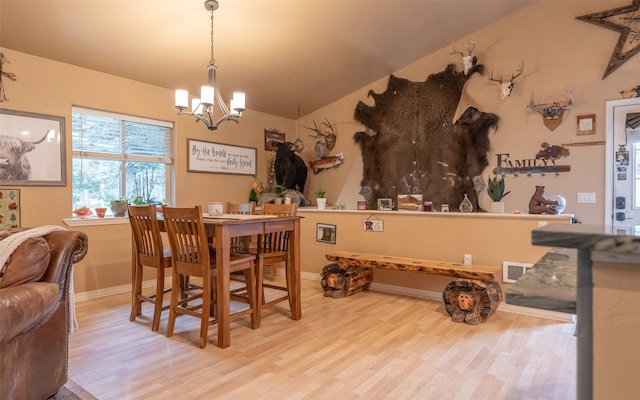 dining room featuring a chandelier, lofted ceiling, and light wood-type flooring