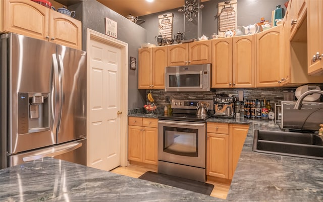 kitchen featuring stainless steel appliances, sink, light wood-type flooring, and backsplash