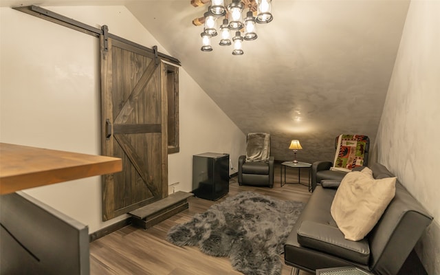 sitting room with lofted ceiling, a barn door, and hardwood / wood-style floors