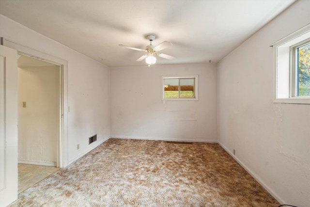 spare room featuring ceiling fan, a wealth of natural light, and light colored carpet