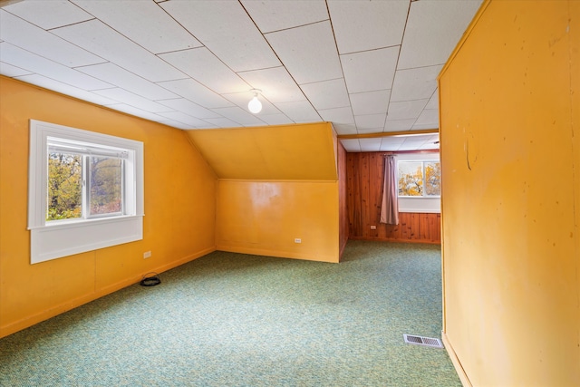 bonus room featuring wood walls, vaulted ceiling, and carpet