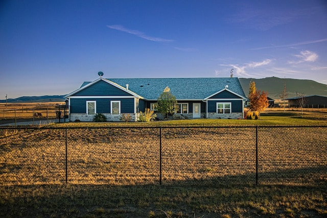 ranch-style house with a mountain view, fence, and stone siding