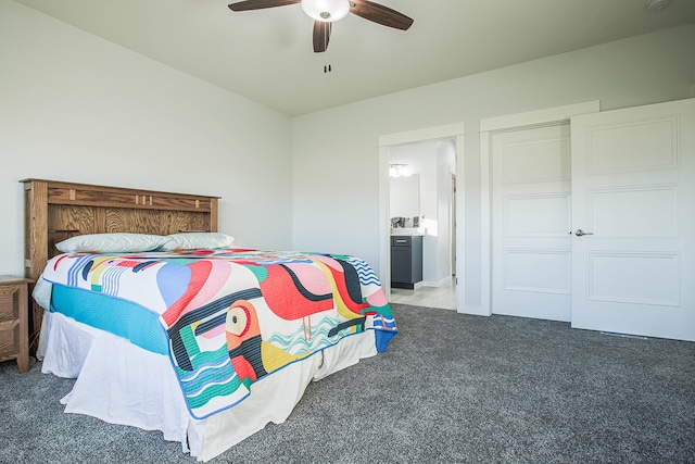 bedroom with connected bathroom, dark colored carpet, and ceiling fan