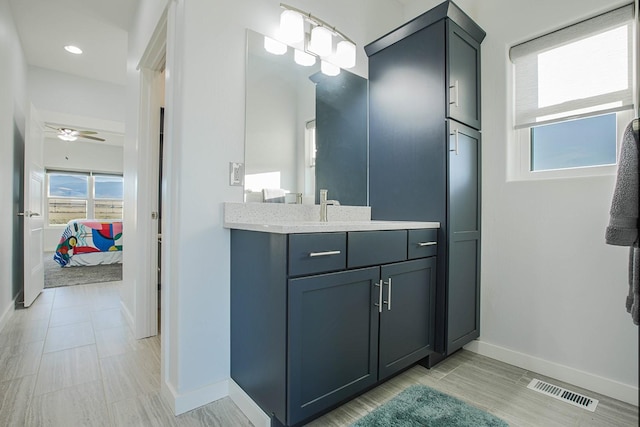ensuite bathroom with baseboards, vanity, and a ceiling fan