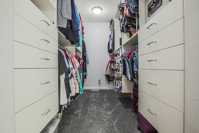 walk in closet with dark carpet