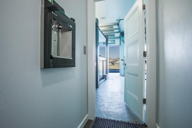hallway featuring carpet and baseboards