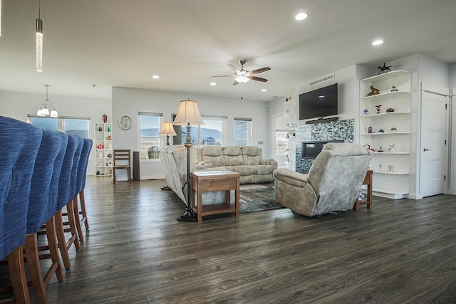 living room featuring a ceiling fan, a glass covered fireplace, dark wood-style floors, and recessed lighting