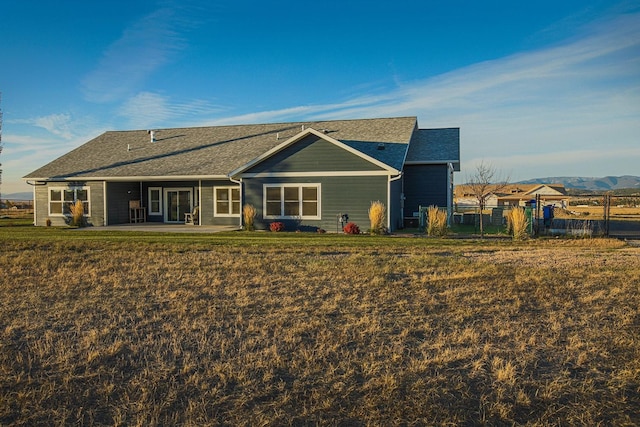 rear view of property with a shingled roof and a patio