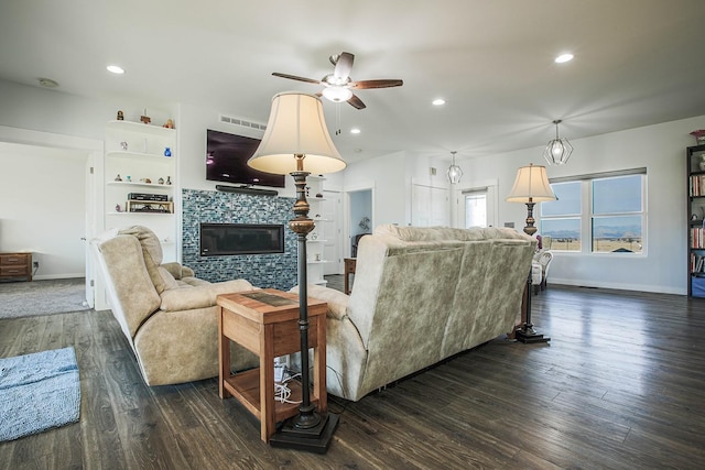 living area with a ceiling fan, dark wood-type flooring, a glass covered fireplace, baseboards, and recessed lighting