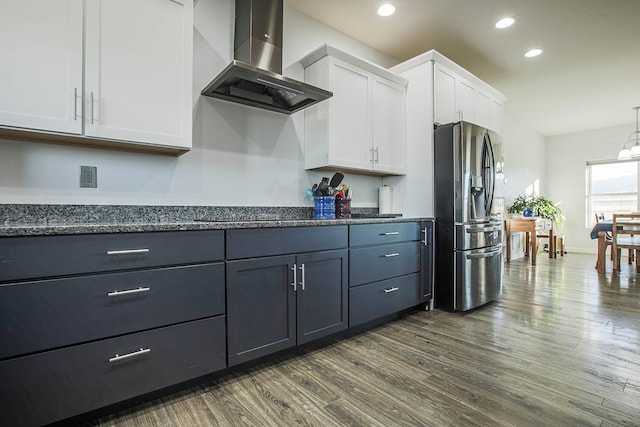 kitchen featuring stainless steel fridge with ice dispenser, wall chimney exhaust hood, dark wood finished floors, white cabinets, and recessed lighting