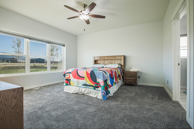 bedroom with dark colored carpet, multiple windows, and ceiling fan