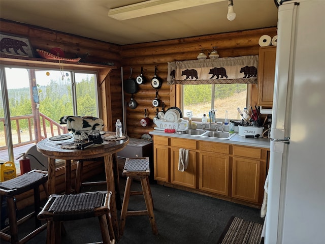 kitchen with sink, rustic walls, a healthy amount of sunlight, and white fridge