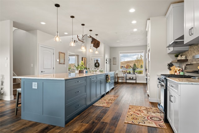 kitchen featuring a spacious island, white cabinets, hanging light fixtures, and range