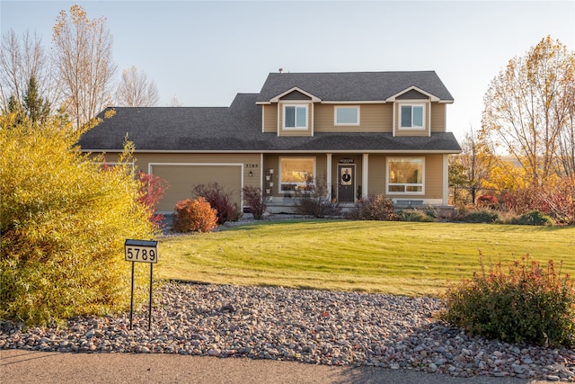 view of front of property featuring a front yard, a garage, and a porch