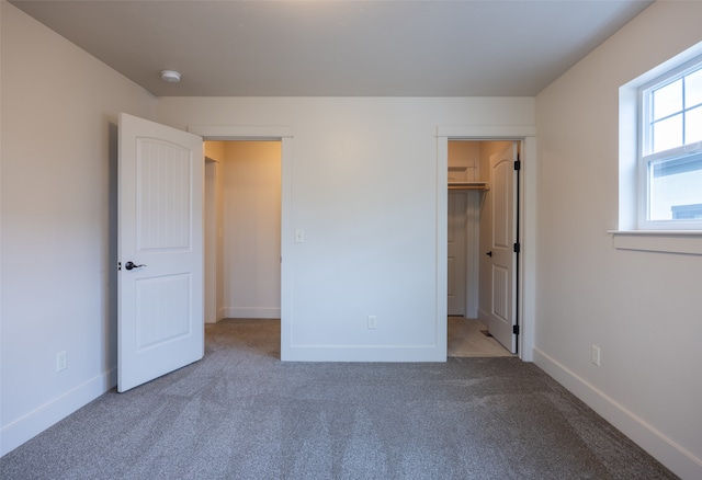 unfurnished bedroom with a spacious closet and carpet