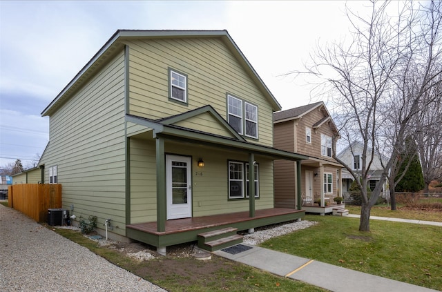 view of front of home featuring covered porch, central AC unit, and a front yard