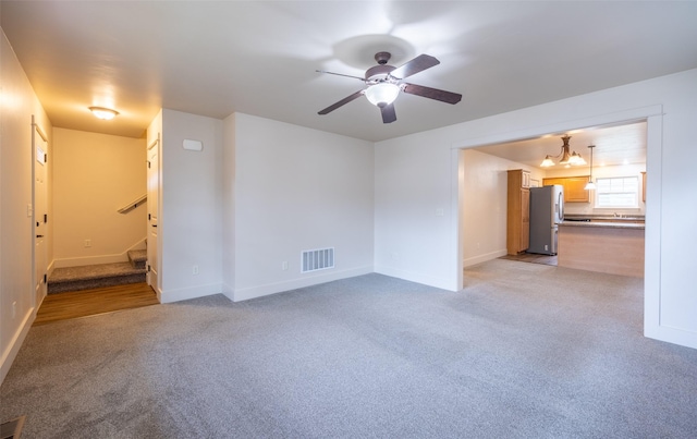 unfurnished living room with light carpet and ceiling fan with notable chandelier