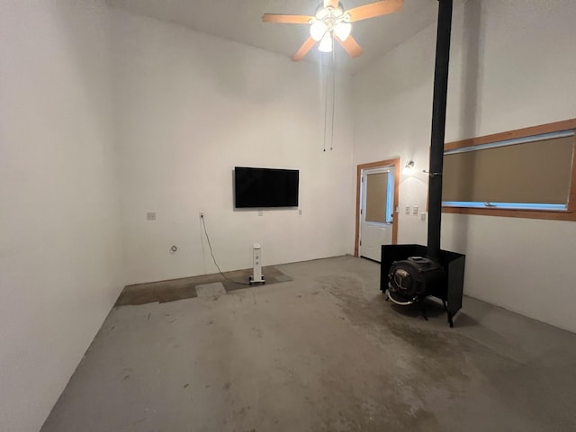 9330 US Highway 2 W, Marion, MT 59925 - unfurnished living room featuring a wood stove, unfinished concrete floors, ceiling fan, and high vaulted ceiling