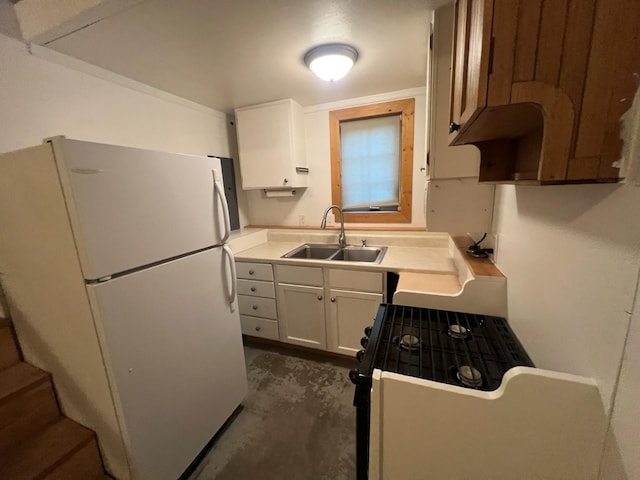 9330 US Highway 2 W, Marion, MT 59925 - kitchen with freestanding refrigerator, a sink, white cabinetry, concrete floors, and range with gas stovetop