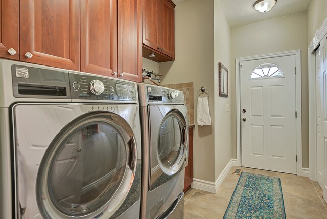 washroom with light tile patterned floors, cabinets, and washing machine and clothes dryer