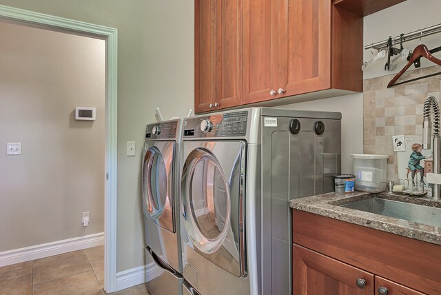 laundry area with sink, washing machine and clothes dryer, light tile patterned floors, and cabinets