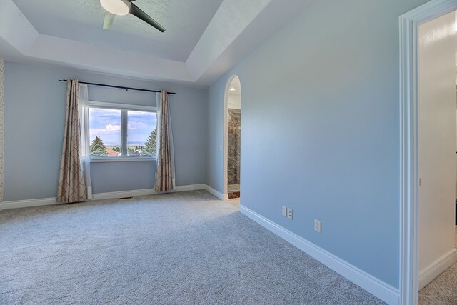 carpeted empty room featuring a tray ceiling and ceiling fan