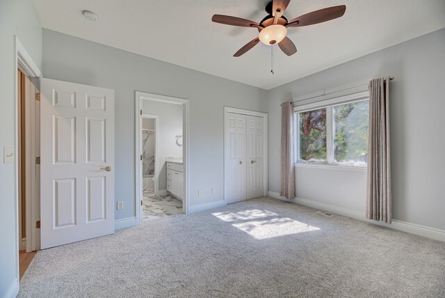 unfurnished bedroom with ensuite bath, light colored carpet, and ceiling fan