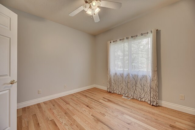 empty room with a textured ceiling, light wood-type flooring, and ceiling fan