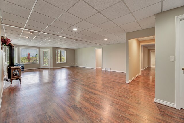 interior space with hardwood / wood-style floors, a paneled ceiling, and a wood stove