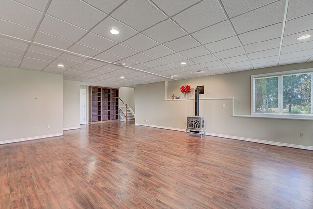 interior space with a paneled ceiling, wood-type flooring, and a wood stove