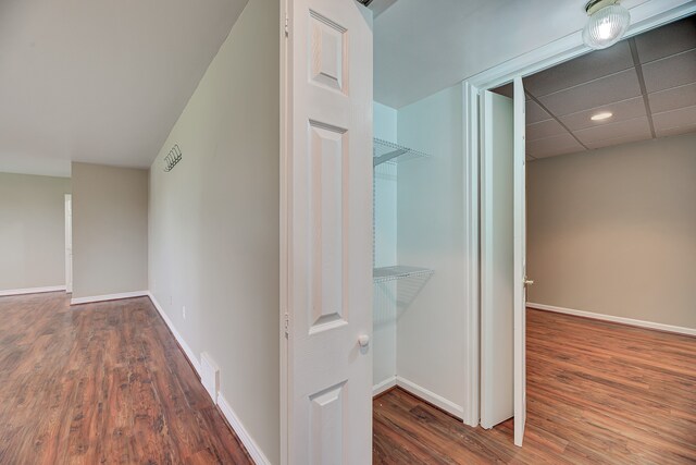 hallway featuring a paneled ceiling and dark wood-type flooring