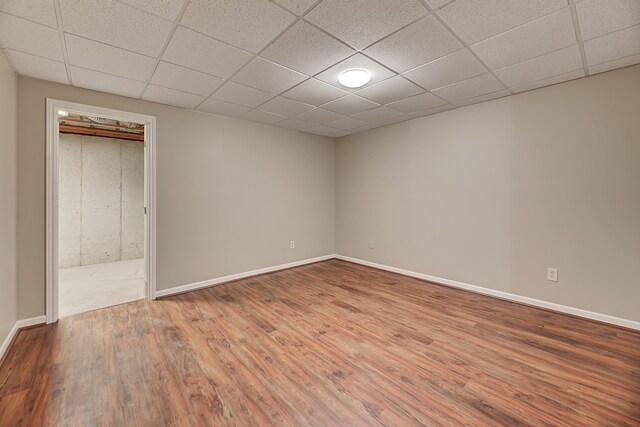 empty room with hardwood / wood-style floors and a drop ceiling