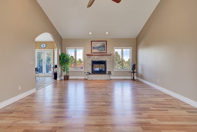 unfurnished living room featuring high vaulted ceiling, a fireplace, light wood-type flooring, and ceiling fan