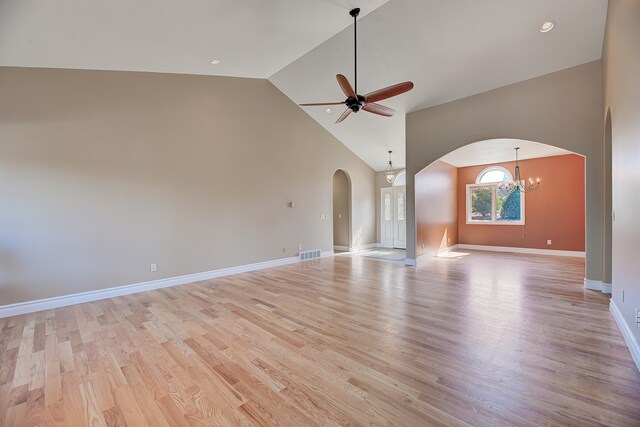 unfurnished living room with light hardwood / wood-style flooring, ceiling fan with notable chandelier, and high vaulted ceiling