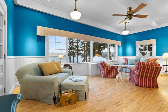 sitting room with ceiling fan, wood-type flooring, and beamed ceiling