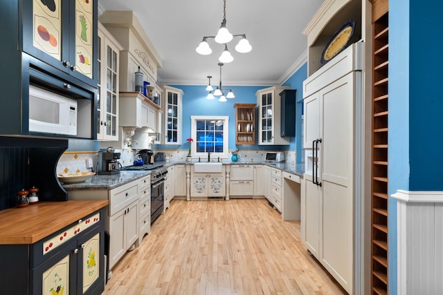 kitchen featuring pendant lighting, crown molding, high end range, backsplash, and white cabinets