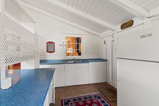 kitchen with wood walls, white cabinetry, sink, white refrigerator, and dark parquet flooring