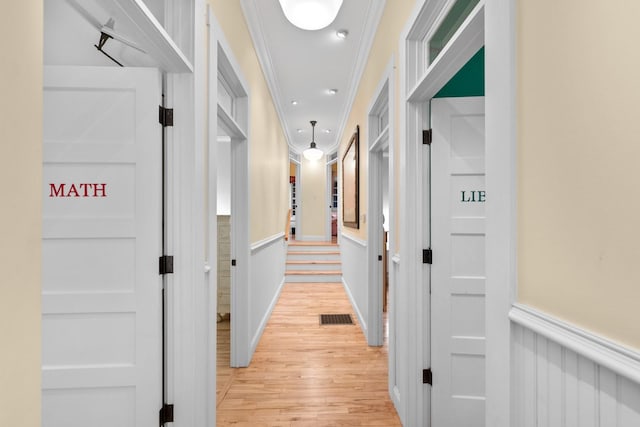 hallway with crown molding and light wood-type flooring